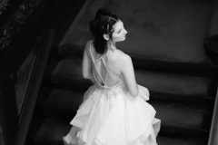 Black and white image of a woman standing one the stairs in a white wedding dress