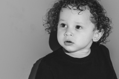 Black and white image of a toddler boy with curly hair looking off into the distance