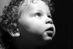 Black and white image of a toddler boy with curly hair looking up